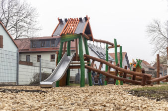 ein Kinderspielplatz mit einem Spielturm aus Holz