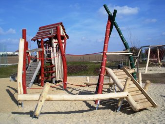 große Sandfläche mit Kletterturm aus Holz und verschiedenen Kletterelemeneten