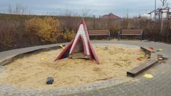 großer runder Sandkasten mit rotem Spielhaus in Form einer Rakete