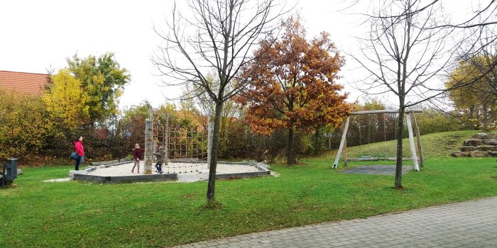 Foto: Spielplatz Urbicher Weg © Stadtverwaltung Erfurt Kletterkombination in Sandkiste und Doppelschaukel auf Grünfläche mit Bäumen