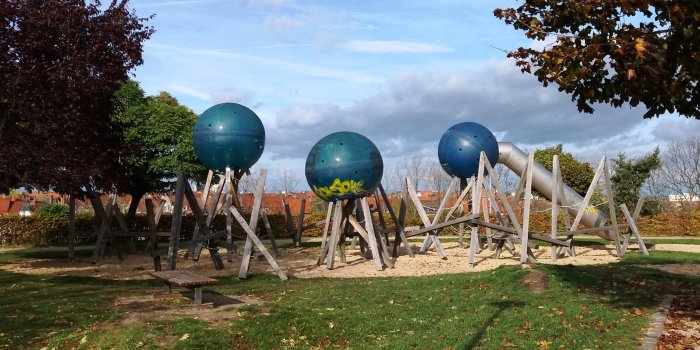 Klettergerüst aus Holz mit großen blauen Kugeln und Röhrenrutsche