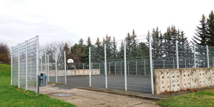 eingezäunter Bolzplatz und Basketballanlage mit Ständer und Korb