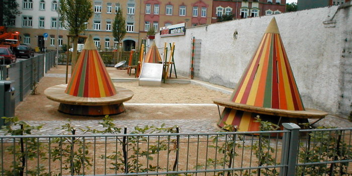 Foto: Spielplatz Schweriner Straße: Sitzkegel und Podestrutsche © Stadtverwaltung Erfurt kleine Sandfläche mit breiter Rutsche und zwei große bunte Kegel mit Sitzflächen