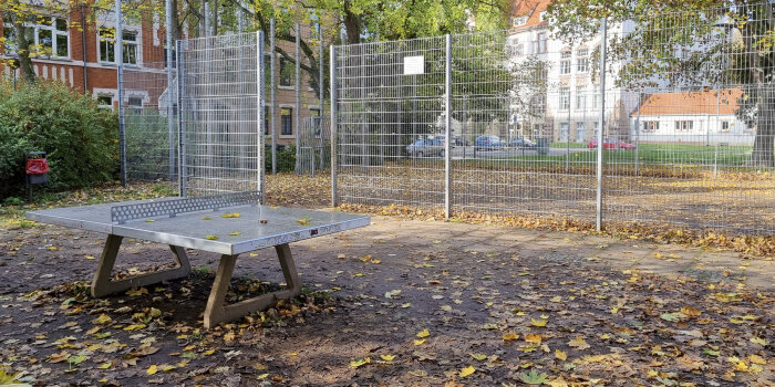 Foto: Spielplatz Schlüterstraße © Stadtverwaltung Erfurt eine Tischtennisplatte, dahinter ein eingezäunter Bolzplatz