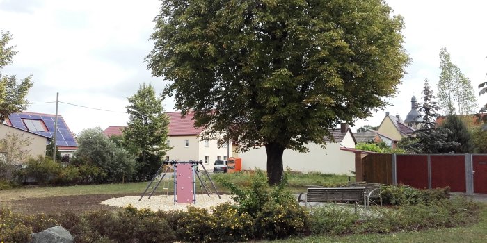 Foto: Spielplatz Kühnhausen Platz/Gutsstraße - "Bäckerplatz" © Stadtverwaltung Erfurt Spielgerät auf Freifläche mit Sitzbank und Baum