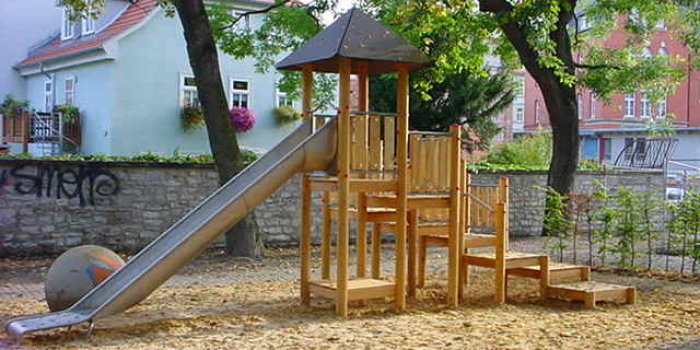 kleine Sandfläche mit Kletterturm aus Holz und Rutsche