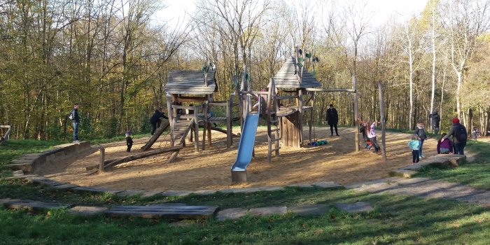 großer Sandfläche mit zwei Klettertürmen aus Holz und Rutsche