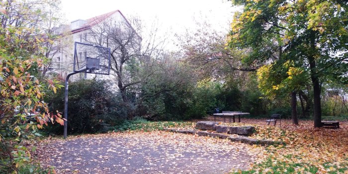 Basketballfläche mit Ständer und Korb, Tischtennisplatte aus Beton und Sitzecke aus Steinen