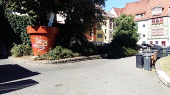 Gepflasterte Fläche und Mülltonnen vor Häuserreihe