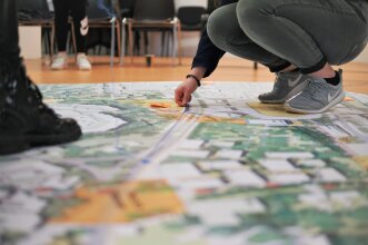 Jugendliche beim Workshop zur "Neuen Mitte" am 4. April. Jugendliche legen Wegebeziehungen auf einem Lageplan beim Workshop zur "Neuen Mitte" am 4. April.