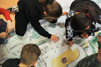 Kinder legen Wegebeziehungen auf einem Lageplan beim Workshop zur "Neuen Mitte" am 4. April.