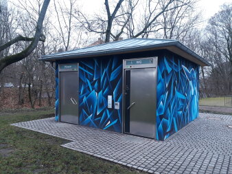 Quadratischer Flachbau mit Schrägdach aus Metall, Eingangstüren aus Edelstahl und Graffiti in Blautönen an Fassade