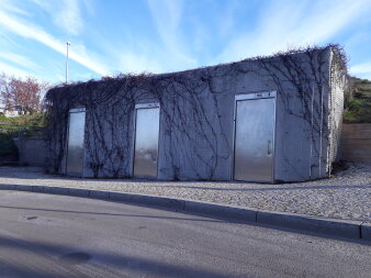 eingeschossiger Flachbau mit Fassade aus Sichtbeton und drei Eingangstüren aus Edelstahl 