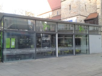 rechteckiger Ergeschossbau mit Flachdach und Glasfassade vor der Kaufmännerkirche  