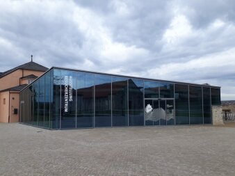 viereckiger Flachbau mit Glasfassade und großer, senkrechter Aufschrift Auststellung Besucherzentrum 