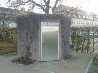 Sechseckiger Baukörper aus Sichtbeton mit Edelstahltüren 