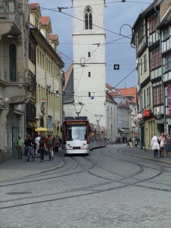 Es ist eine Straßenbahn dargestellt, die aus Richtung Marktstraße auf den Domplatz fährt.