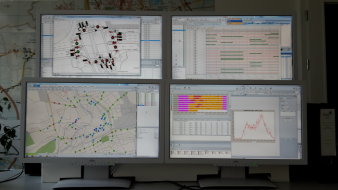 vier Monitore mit textlicher und geografischer Darstellung