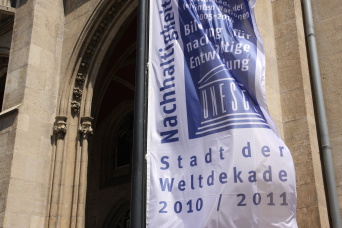 Vor dem Rathaus weht eine weiße Fahne mit blauer Schrift.