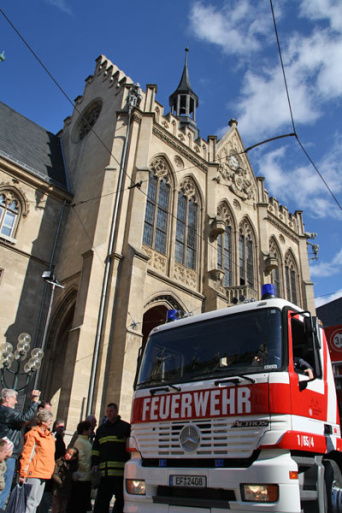 Ein Feuerwehrauto und Schaulustige vor dem Rathaus.