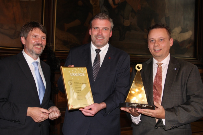 Preisträger Ulrich Haage mit Oberbürgermeister Andreas Bausewein und Gerald Bitterberg bei der Preisübergabe im Rathausfestsaal, Herr Haage hält den goldenen Preis in den Händen, der OB die Urkunde.