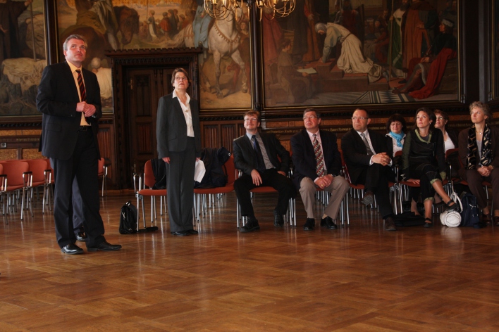 Foto: Empfang der Gäste © Stadtverwaltung Erfurt Eine Person erklärt acht Anwesenden die Gemälde im Rathausfestsaal.