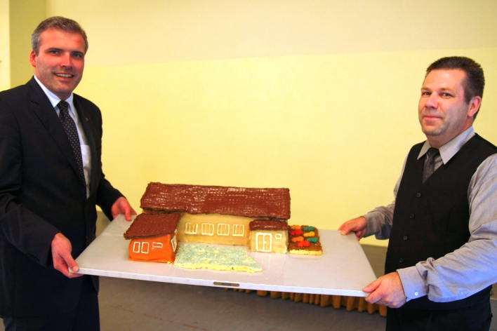 Oberbürgermeister Andreas Bausewein (l.) und Peter Richter (r.) halten in ihrer Mitte das Bürgerhaus in Kuchenformat auf einer Platte.