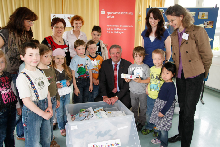 Foto - Die Kinder und Erzieherinnen der Kitas Regenbogenland, Riethzwerge und Vollbrachtfinken freuen sich auf spannende Experimente mit ihren neuen "Forscherboxen", die von OB Andreas Bausewein, der auch Kuratoriumsvorsitzender der Sparkassenstiftung ist, übergeben wurden.