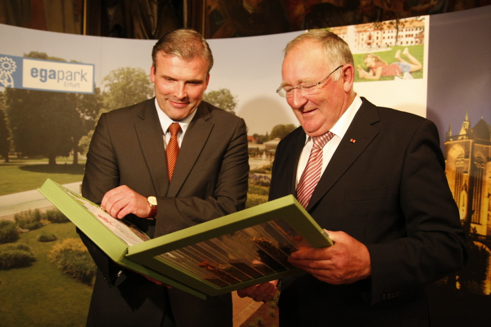 Der Erfurter Oberbürgermeister übergibt dem Chef der Buga-Gesellschaft eine große Mappe.