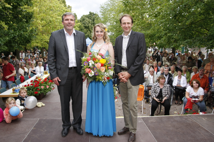 Blumenkönigin mit Blumenstrauß und Publikum im Hintergrund