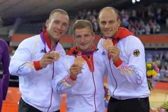 Drei Radsportler zeigen die Medaillen