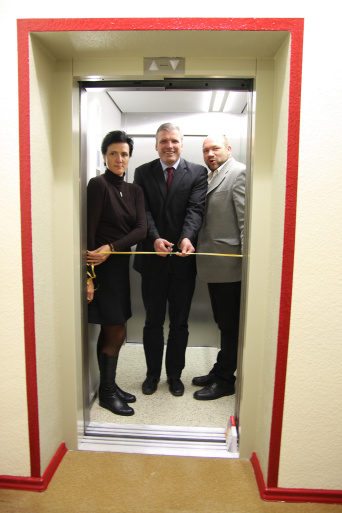 Architektin Jacqueline Schmidt, Oberbürgermeister Andreas Bausewein und VHS-Leiter Torsten Haß stehen im nagelneuen Aufzug der Volkshochschule