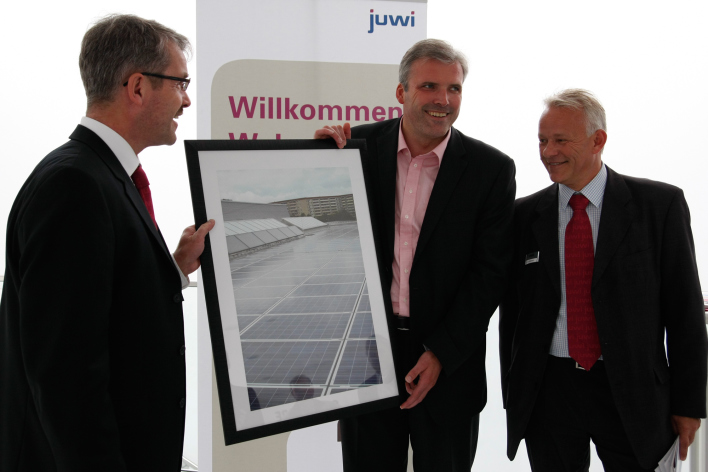 Zwei Manager und der Oberbürgermeister halten symbolisch ein Foto der Photovoltaik-Anlage in Händen