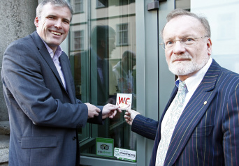 Oberbürgermeister Andreas Bausewein und Jochen Spilker kleben den WelCome-Aufkleber gut sichtbar an die Tür des Restaurants Siju.