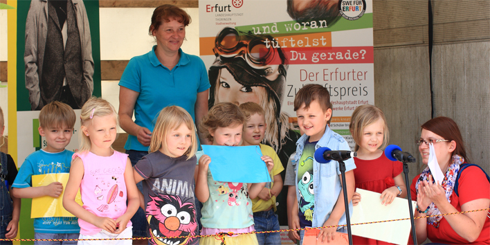 Kindergartenkinder singen auf einer Bühne ein Lied.