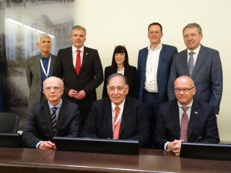 Sieben Männer und eine Frau, darunter die Oberbürgermeister der deutschen Partnerstädte, posieren für das Foto hinter einem Tisch.  