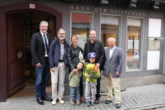 Vier Erwachsene, darunter eine Frau und zwei kleine Kindern stehen auf der Krämerbrücke vor dem Haus der Stiftung Krämerbrücke.