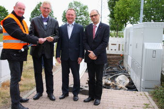 Der Leiter des Amtes für Wirtschaftsförderung, der Kerspelebenr Ortsteilbürgermeister und zwei Vertreter der Telekom an der Baugrube mit Erdkabekabeln.