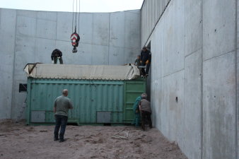 Ein Container steht im Außengelände der Elefantenanlage direkt vor der Tür, durch die der Elefant die Anlage betreten soll, Menschen stehen um und auf dem Container. 