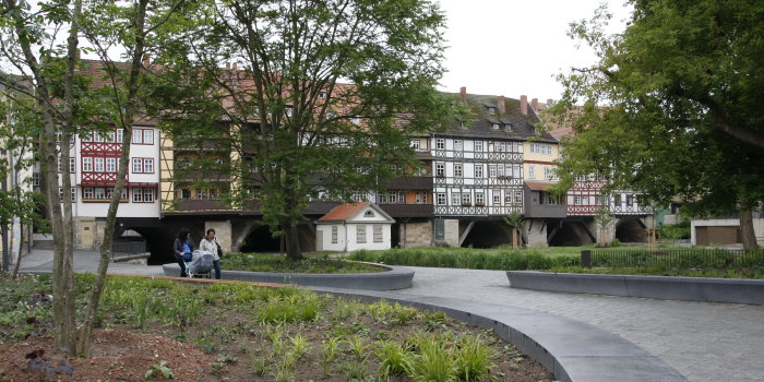 Zwei Frauen schieben einen Kinderwagen über die neu gestaltete Freifläche hinter der Krämerbrücke, welche man im Bildhintergrund sieht. 