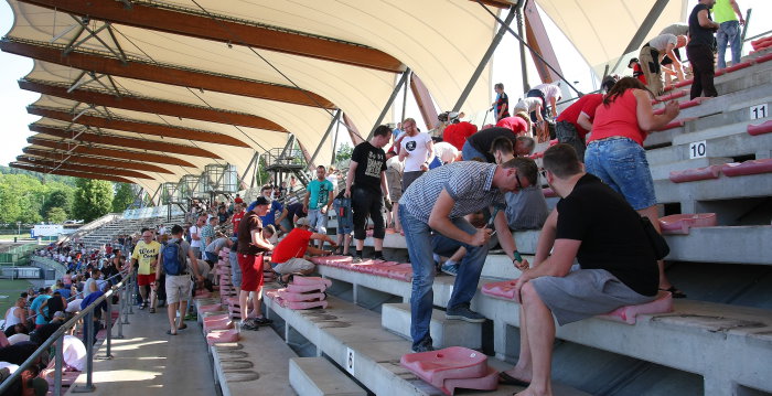 mehre hundert Fans auf einer Stadiontribüne beim Abschrauben von Sitzschalen