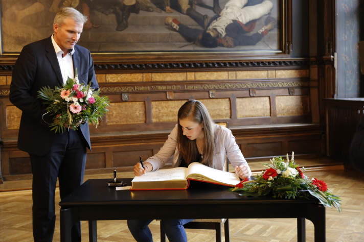Eine junge Frau trägt sich in ein Buch ein.