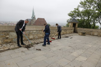 Oberbürgermeister Andreas Bausewein reinigt mit zwei jugendlichen Schülern das Plateau auf dem Petersberg, im Hindergrund sieht man den Dom. 