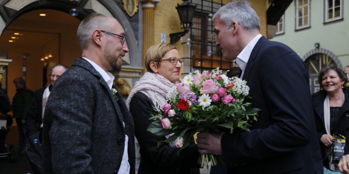 Oberbürgermeister Andreas Bausewein überreicht einem Hochzeitspaar vor dem Portal des Hochzeitshauses einen Strauß Blumen. 