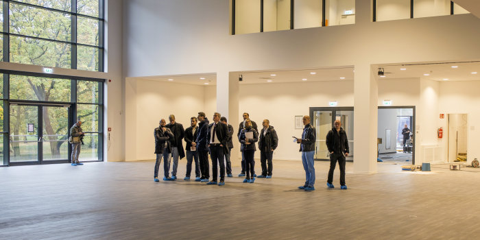 Foto: Foyer des Multifunktionsgebäudes © Stadtverwaltung Erfurt Mehrere Personen besichtigen einen großen leeren Saal.