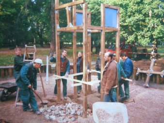 In einem Park wird von zehn Garten- und Landschaftsbauern ein Klettergerüst auf einem Spielplatz errichtet.