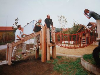 Auf einem neu gebauten Klettergerüst in einer Nachbarschaft posieren drei Männer, die von einem Fotografen zu einem Pressefoto gebeten wurden.