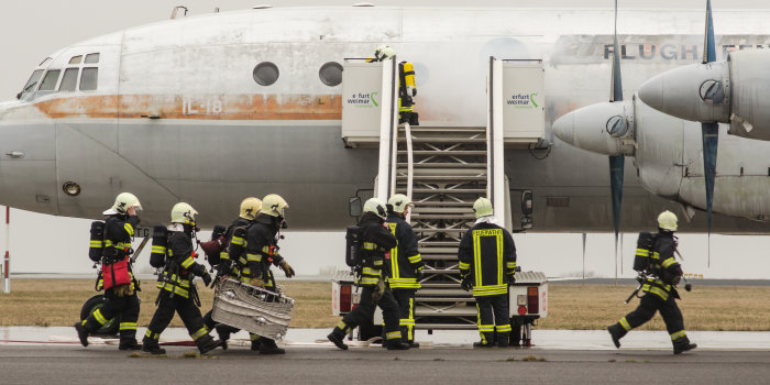 Foto: Feuerwehreinsatz am Flughafen © Stadtverwaltung Erfurt Einsatzkräfte der Feuerwehr stehen vor einem Flugzeug, aus dem es qualmt