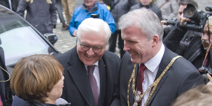 Foto: Besuch des Bundespräsidenten Fank-Walter Steinmeier © Stadtverwaltung Erfurt Ein Mann mit Amtskette begrüßt einen Mann und eine Frau, umringt von vielen Fotografen