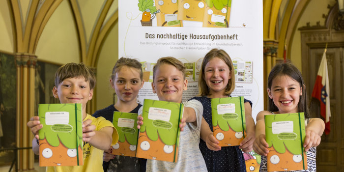 Fünf Grundschüler zeigen jeweils ihr Hausaufgabenheft